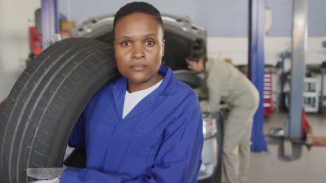 Video-of-african-american-female-car-mechanic-holding-tyre