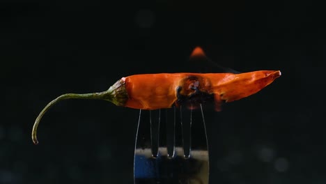 close up shot of red chili pepper with flame burning out with smoke rising