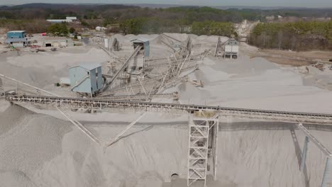 aerial footage rotating around a group of conveyor belts moving rock in a quarry.