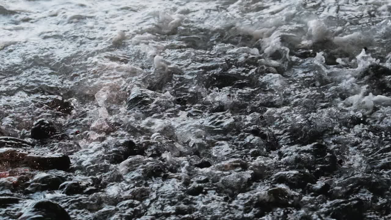 바위 해변 위로 흐르는 파도의 클로즈업