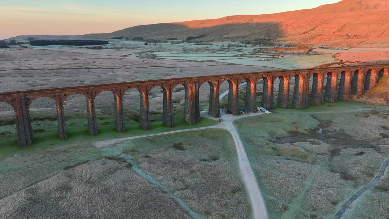 겨울 에 해가 뜨면 아치형 철도 다리 에 접근 하는 것