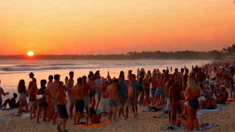 crowded beach at sunset with people enjoying the evening