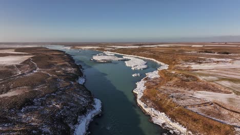 aerial view of urriðafoss waterfall in iceland. the glacial river carves through a winter landscape, with icy shores and rugged terrain. a stunning display of natural power and nordic wilderness.