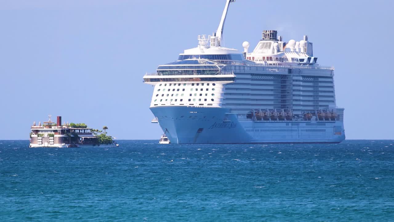 A large cruise ship moves steadily through Phuket's blue waters under clear skies, creating a serene and majestic scene