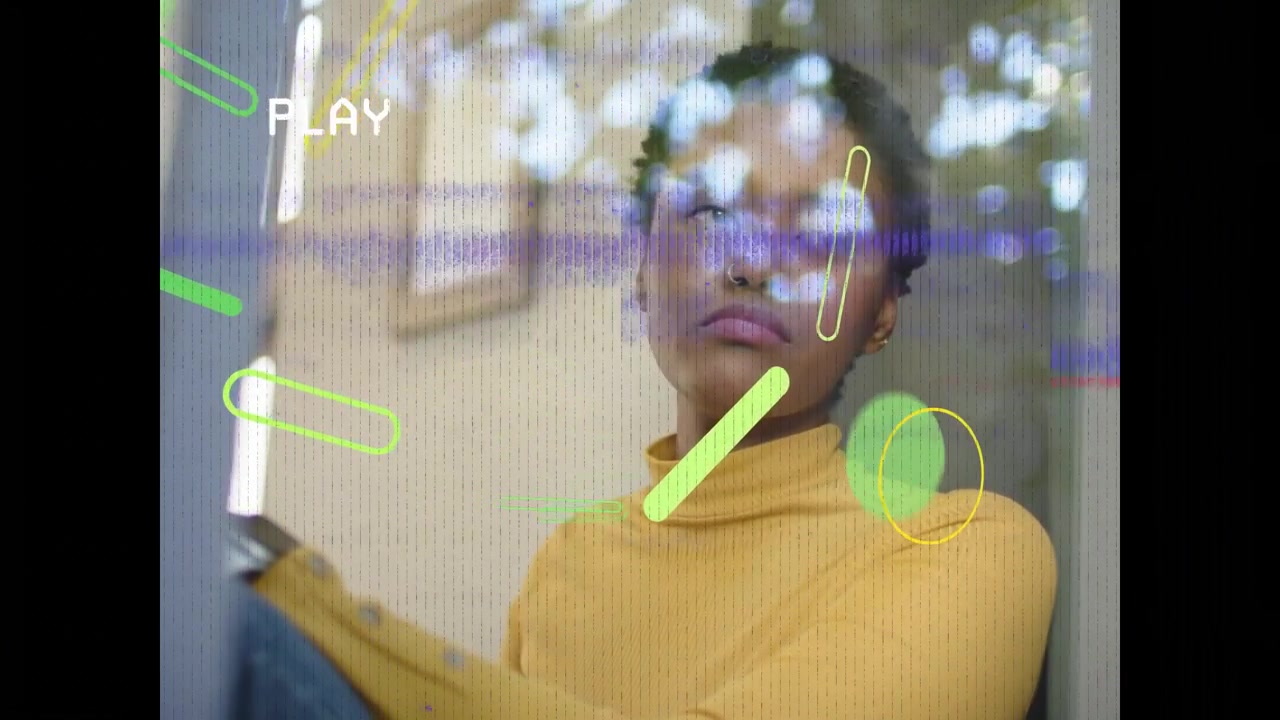 Vertical video: Noticing neon shapes, woman in yellow sweater tilting head by window, tracking PLAY