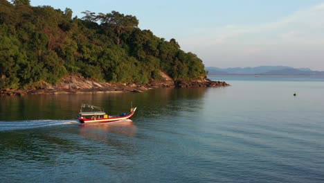 toma de seguimiento aéreo cinematográfico que captura un barco de pesca tradicional en góndola, navegando hacia el océano para pescar en la hermosa hora dorada del atardecer, isla de langkawi, malasia, sudeste de asia