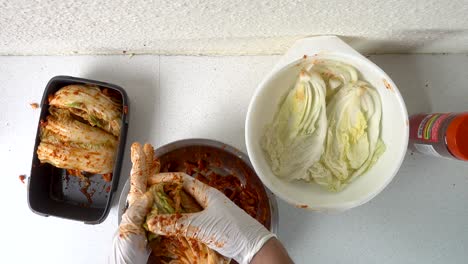 top down look at male hands preparing kimchi cabbage and packing it away