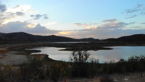 cool aerial drone 4k tracking shot of dried up, drought-stricken irvine lake reservoir in orange, county, southern california with trees in foreground