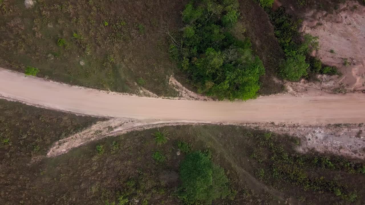 Wide aerial shot of a dirt road surrounded by greenery in Serra da Canastra, Brazil
