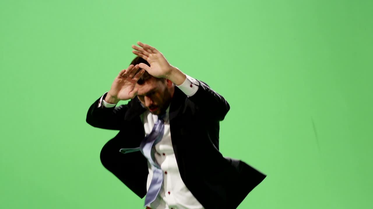 Serious businessman in a suit is running and spreading hands on a mock-up green screen in the background.