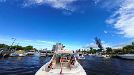 people rest on the beautiful motor boat. fpv drone goes up revealing the panning view of a cityscape around.