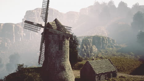 misty mountain landscape with old windmill and cabin