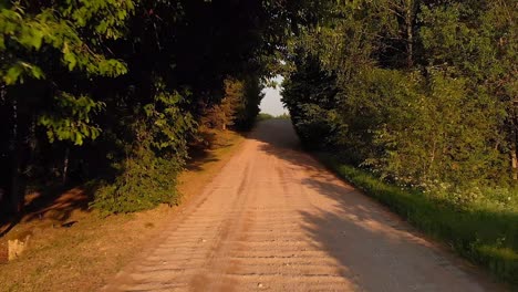 Niedrige-Luftdrohne,-Die-Auf-Einer-Friedlichen-Schotterwegstraße-Im-Park-Fliegt,-Goldene-Stunde