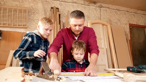 father and sons learning woodworking in a workshop