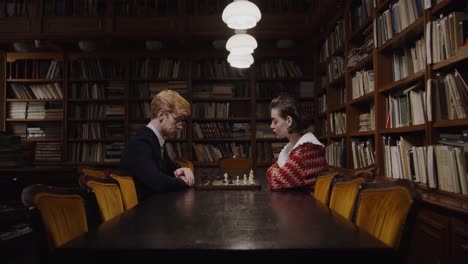 couple playing chess in a library