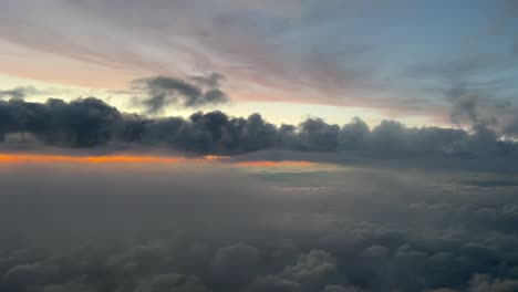 colorful sunset shot from an airplane cabin flying at 12000m high across a cloudy sky