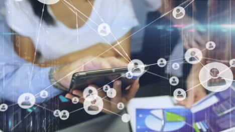 red de iconos de perfil contra la sección media de colegas de oficina que usan tableta digital en la oficina
