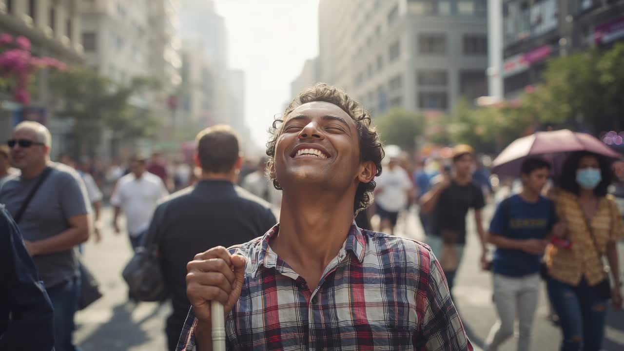 Homem caminhando em rua movimentada da cidade, usando camisa xadrez e segurando bengala branca, com a luz do sol provocando um sorriso