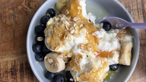 eating breakfast with blueberries, banana, yoghurt and oats with some honey