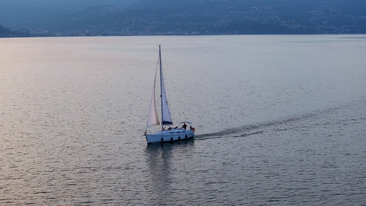 brillo cálido en el agua del lago y un velero navegando a través del encantador lago maggiore en italia