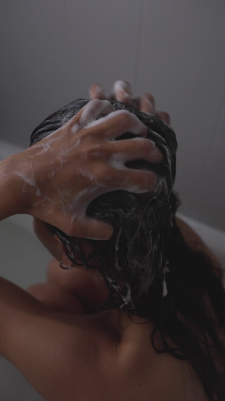Donna che si lava i capelli sotto la doccia