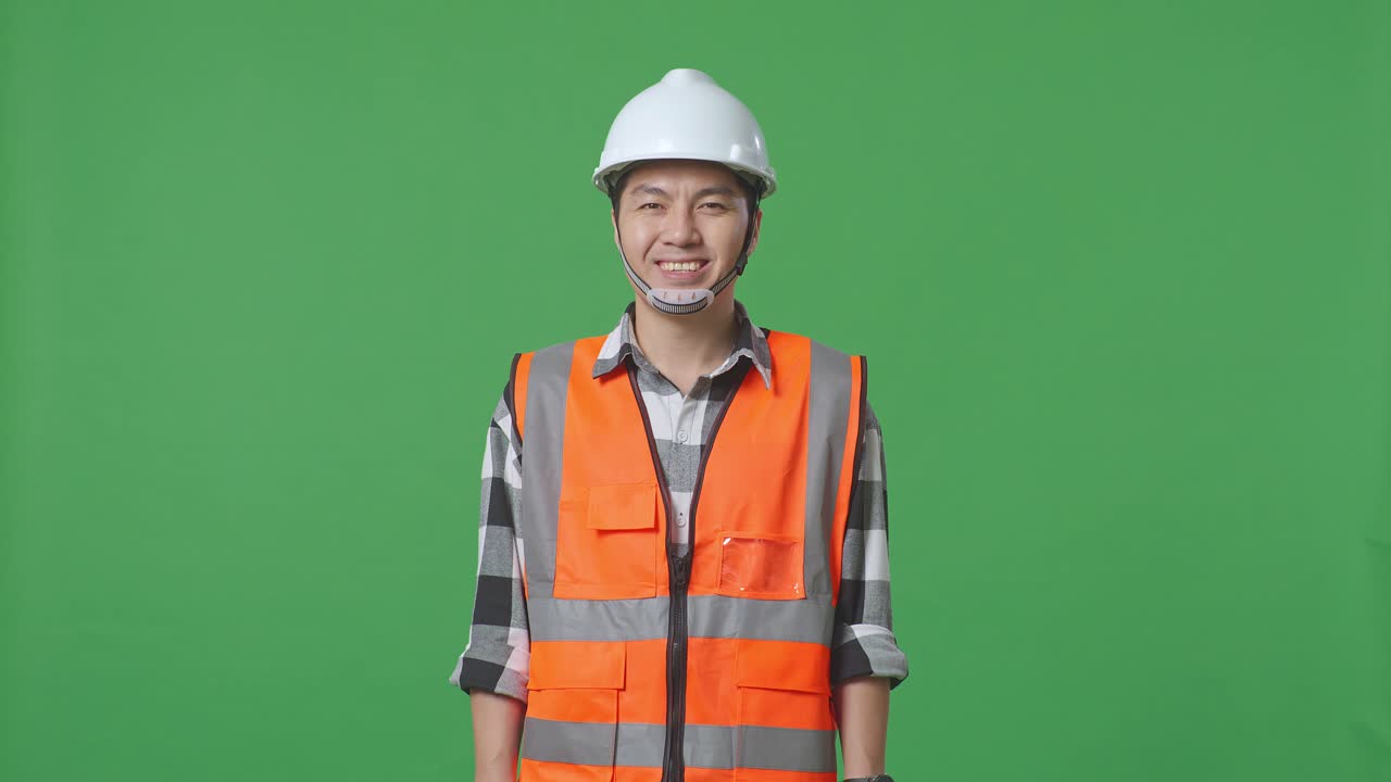 Asian Male Engineer With Safety Helmet Smiling To Camera While Standing In The Green Screen Background Studio