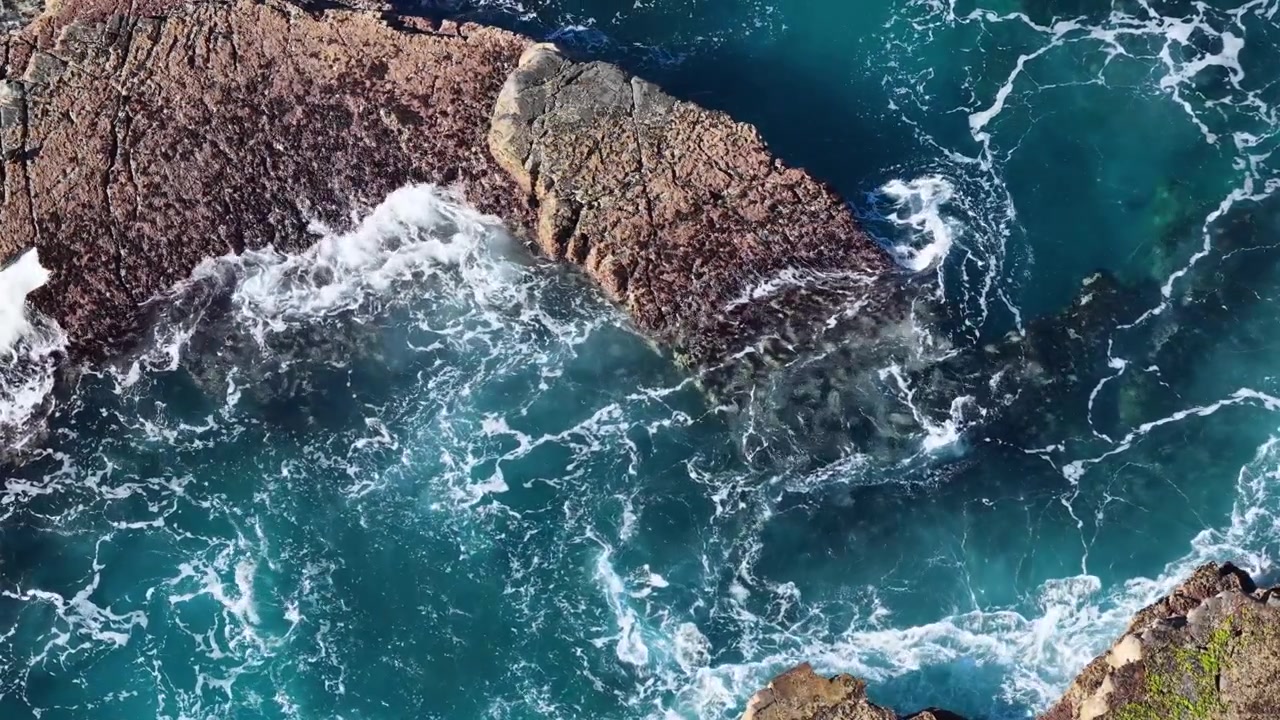Ripresa aerea dall'alto di onde turchesi dell'oceano che si infrangono sulle rocce costiere a Crescent Head, Australia.