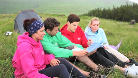 friends on a camping trip chatting together and reading map