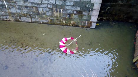 red and white umbrella underwater in a lock chamber, static shot