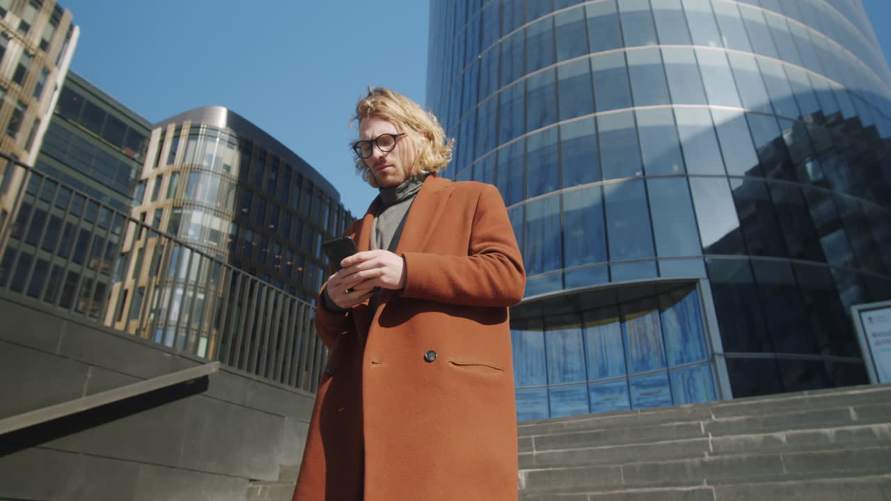 Forretningsmann går i sentrum og bruker smarttelefon