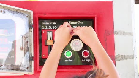 A person operates a coin-operated fuel dispenser in bright daylight at Khao Rang Viewpoint, Phuket, Thailand