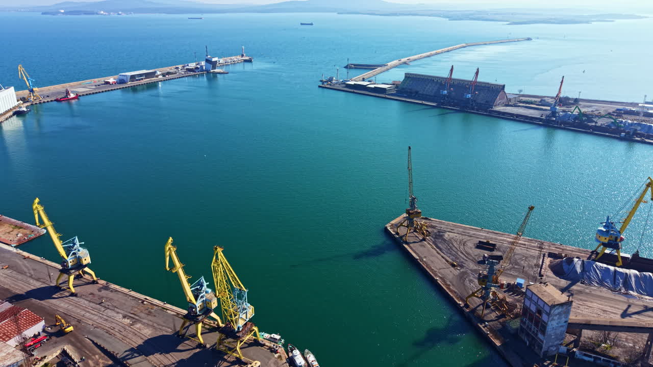 Port area with cranes and ships at work near waterfront in clear weather during daytime