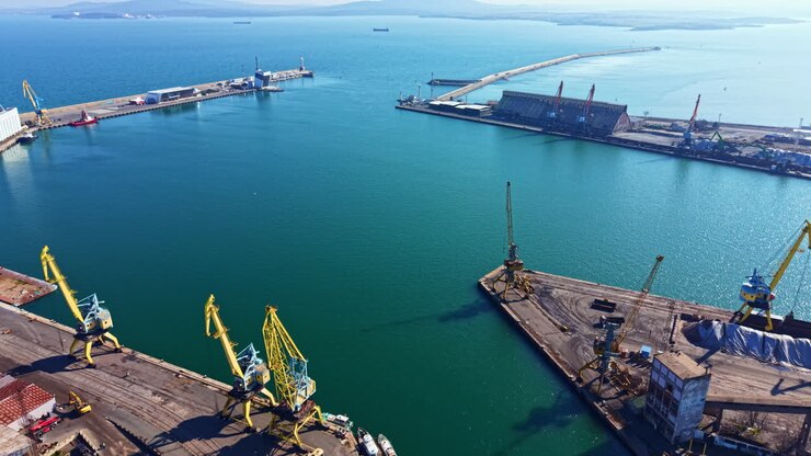 Port area with cranes and ships at work near waterfront in clear weather during daytime