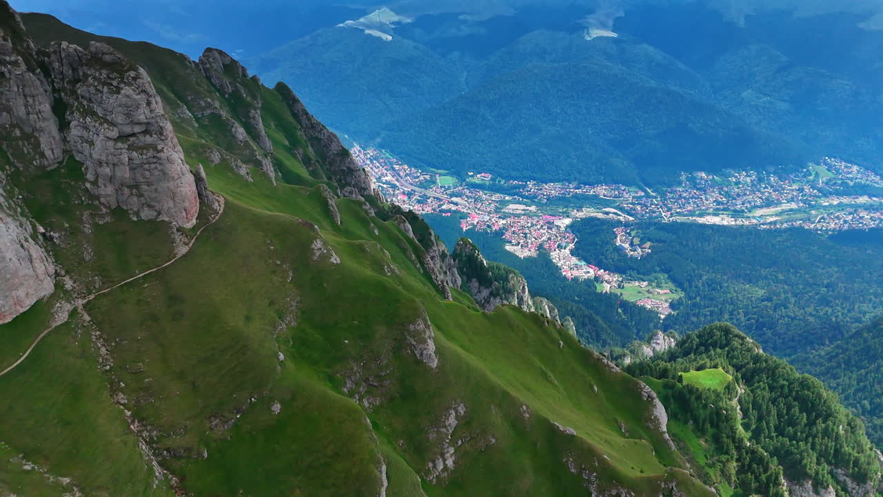 Mountain view overlooking a valley town. A stunning valley town among green mountains under a bright blue sky, highlighting nature's beauty