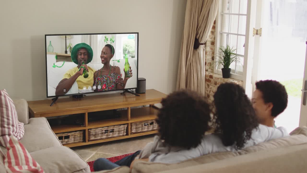 Famiglia afroamericana a casa che usa la smart TV per fare una videochiamata nel giorno di San Patrizio.
