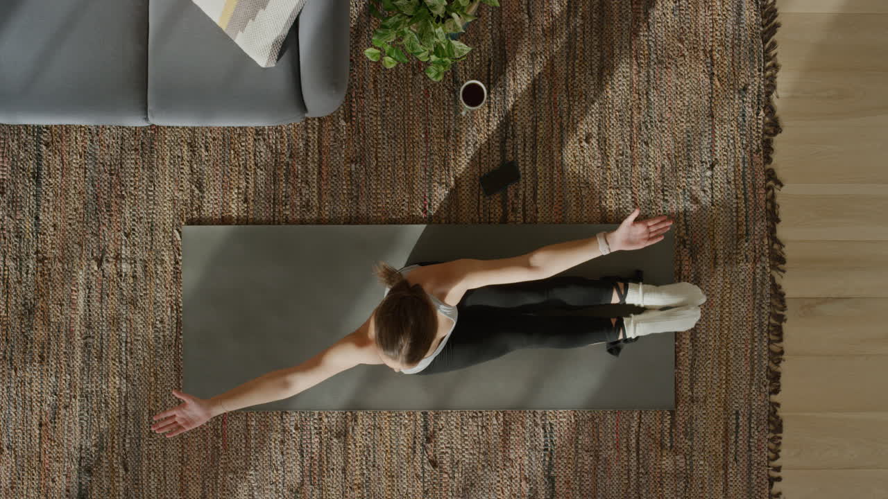vista superior mujer de yoga ejercitando un estilo de vida saludable estirando el cuerpo flexible disfrutando del entrenamiento en casa practicando atención plena en la colchoneta de ejercicios