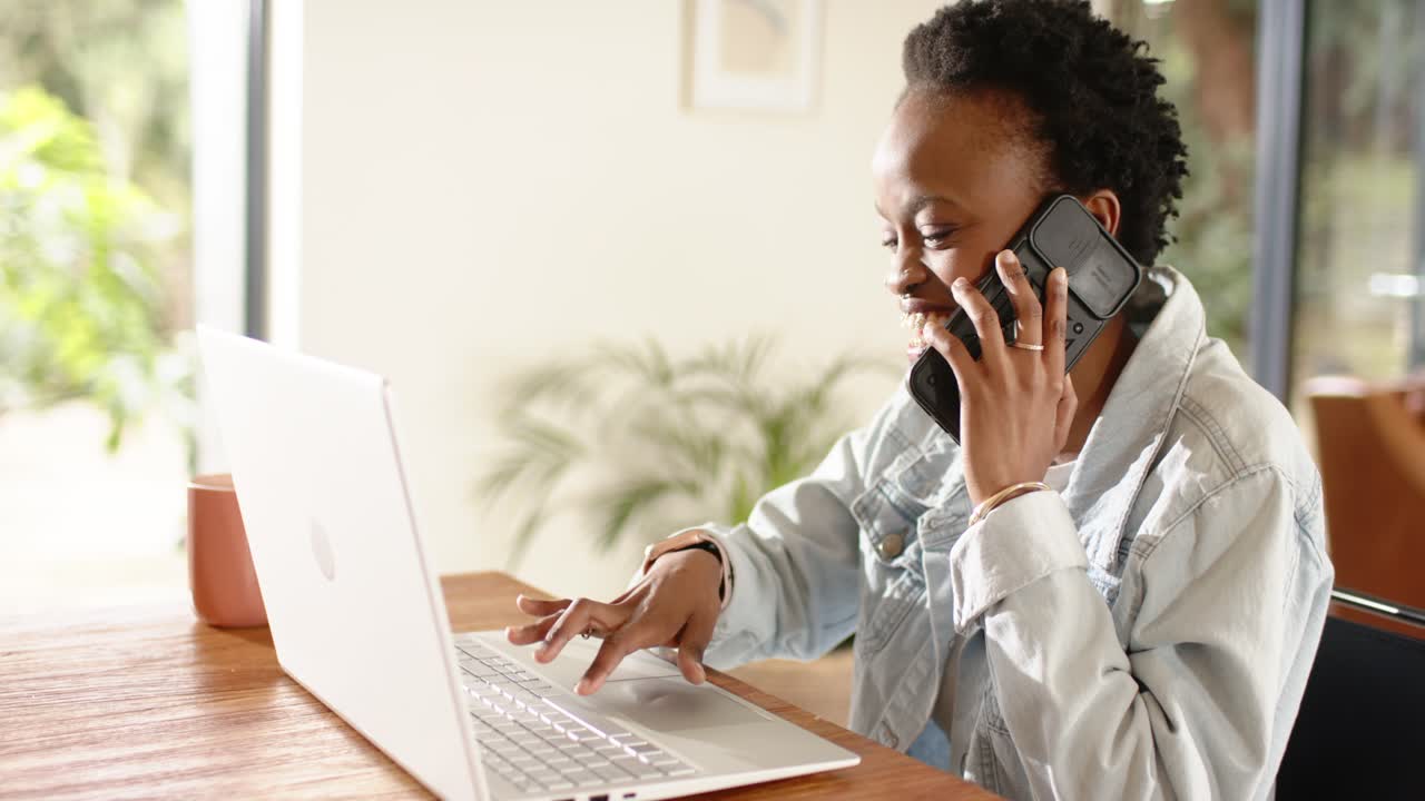 De telefoon gaat, een Afro-Amerikaanse vrouw typt thuis op de toetsen van haar laptop en tikt op haar smartphone voor een werkgesprek.