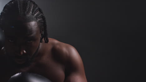 portrait of boxer putting up fists in gloves at start of boxing match with low key lighting and copy space