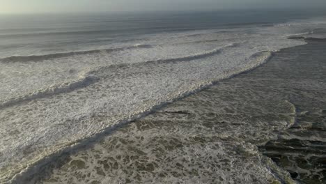 Vista-Aérea-De-Suaves-Olas-Volando-Hacia-Adelante,-Durante-La-Puesta-De-Sol