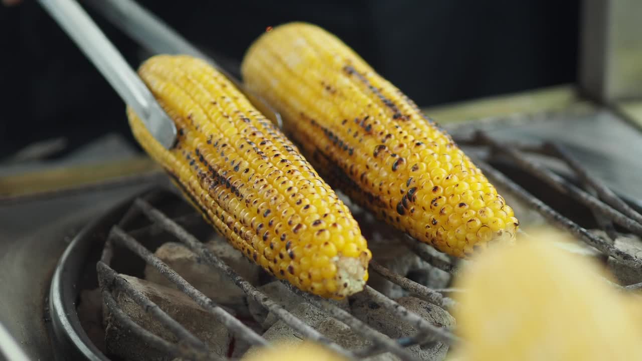 Turning Grilled Corn on the Cob on a Hot Barbecue