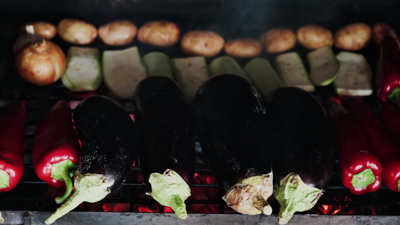 Close up of eggplants, potatoes, onions, peppers and courgettes cooking on a grill