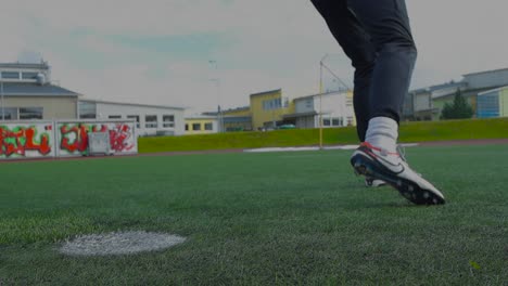 close up footage of a soccer ball being kicked and hit on a soccer stadium during summer time while its cloudy in slow motion. ball is placed on white penalty marking on the short stadium grass.