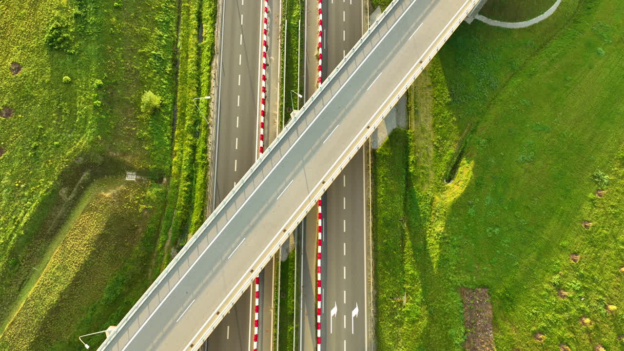 Top down aerial of overpass bridge with multilane highway and red white barriers