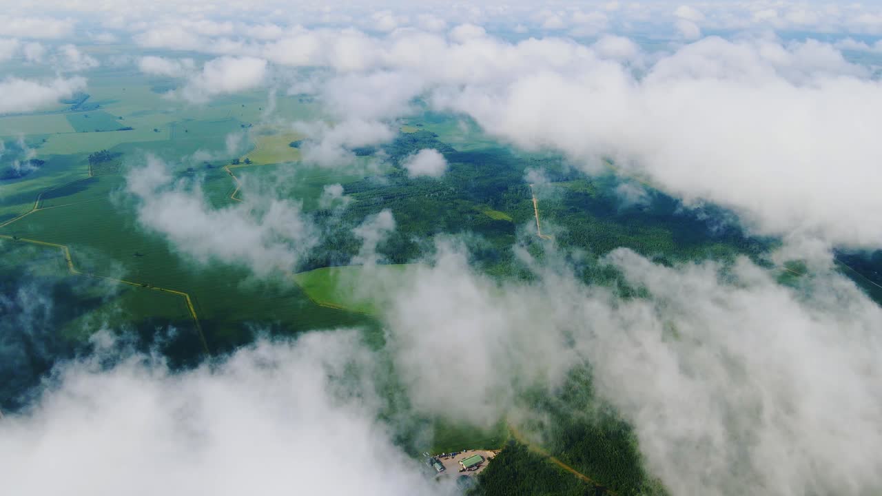 Low-hanging clouds move over peaceful farmland and forest in Northern Europe