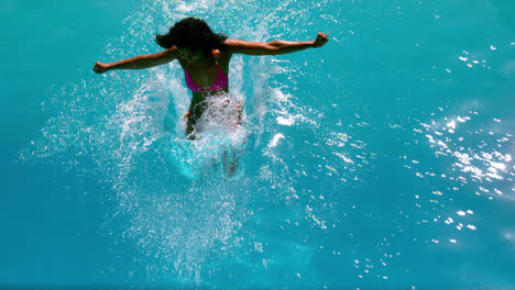 mujer en bikini rosa saltando a la piscina