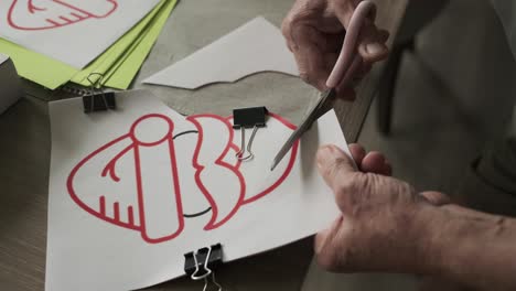 close up of old man cutting along the lines a red santa for christmas decoration