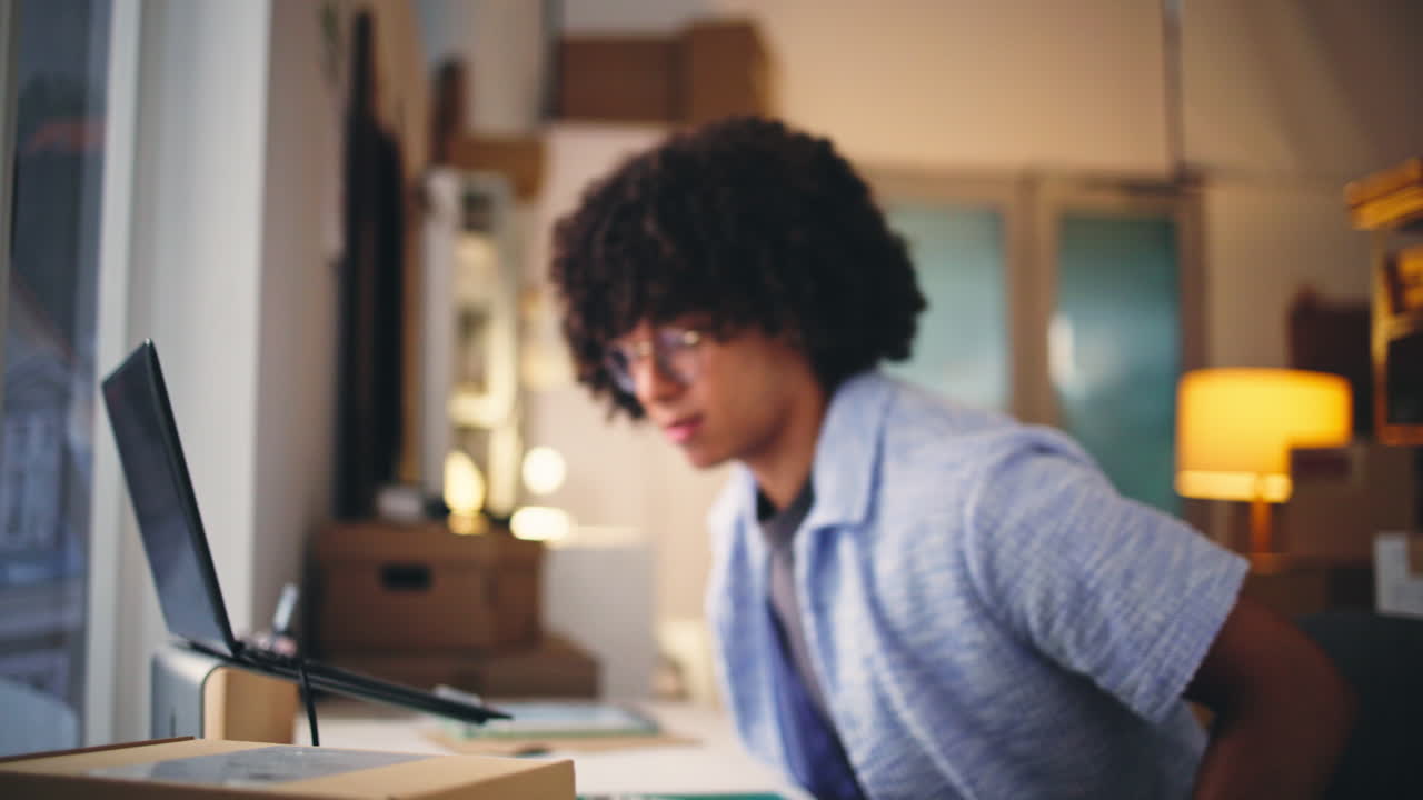 Man Scanning Barcode and Typing on Laptop in Home Office