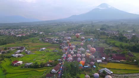 aerial view of colorful air balloon floating on the air with view of rural landscape and mountain on the background