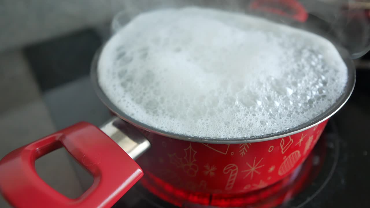 agua hirviendo en una olla de navidad roja en una estufa