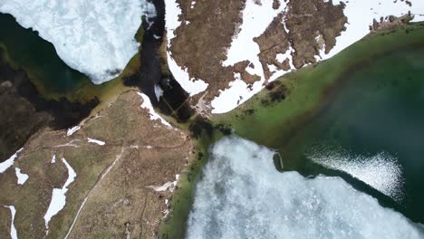 Top-down-aerial-shot-of-frozen-lake-of-Laghi-dei-Piani-in-Dolomiti-National-Park